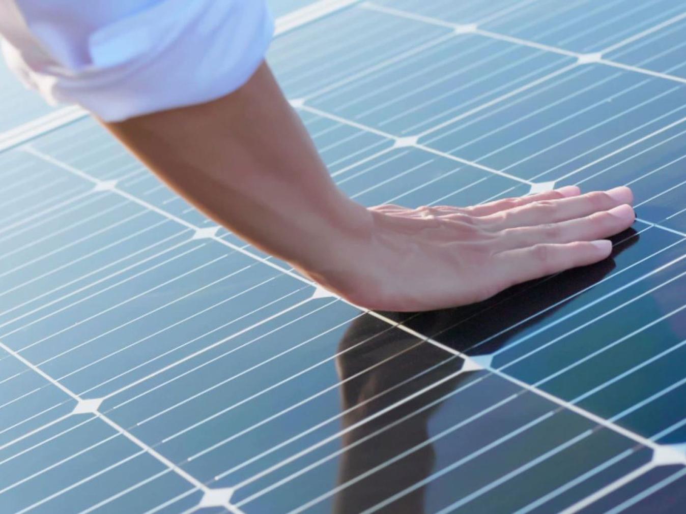 Ruka dotýkajúca sa fotovoltaických modulov. 