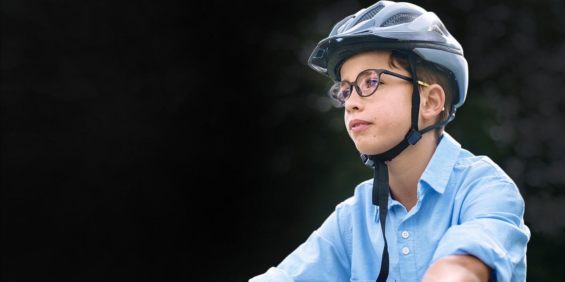 Mladý chlapec v okuliaroch a prilbe zrejme jazdí na bicykli.