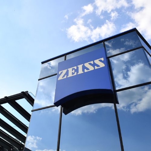 Obrázok modernej presklenej budovy s veľkým logom ZEISS. 