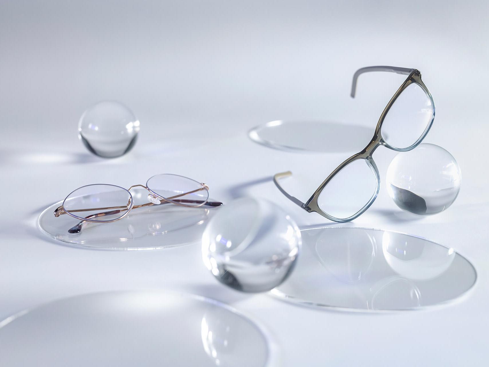 Okuliare so šošovkami ZEISS, ktoré majú povrch DuraVision® Silver a nevykazujú žiadne odrazy v porovnaní s okolitými sklenenými guľami.