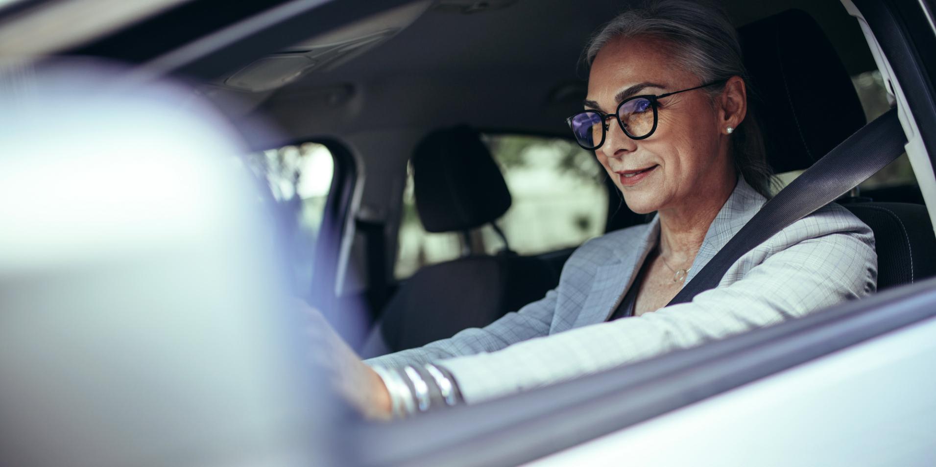 Zrelá žena v aute má na sebe okuliare s šošovkami ZEISS DriveSafe.