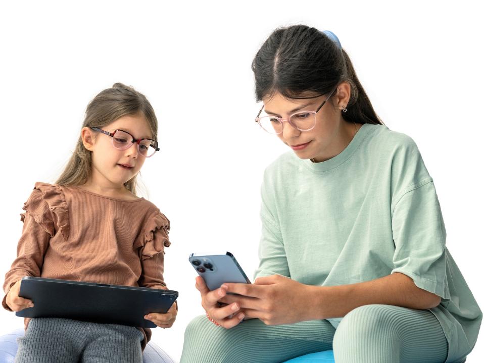 Dve dievčatá pozerajúce sa na digitálne zariadenia v navrhovanej vzdialenosti viac ako 20 cm.