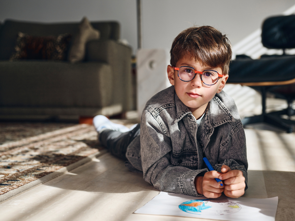 Mladý chlapec s okuliarovými šošovkami ZEISS MyoCare sa pozerá priamo do objektívu.