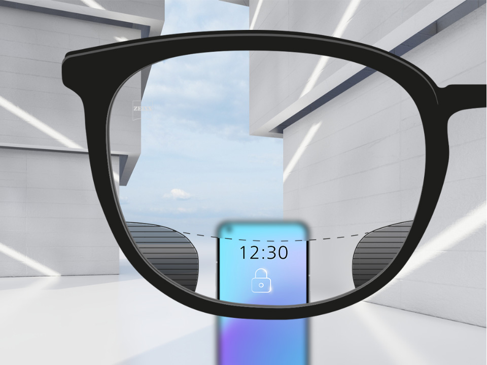Obrázok zorného uhla so šošovkami ZEISS Digital SmartLife so smartfónom a šošovkou, ktoré sú úplne jasné v hornej a dolnej oblasti šošovky, a s malými rozmazanými políčkami vľavo a vpravo.