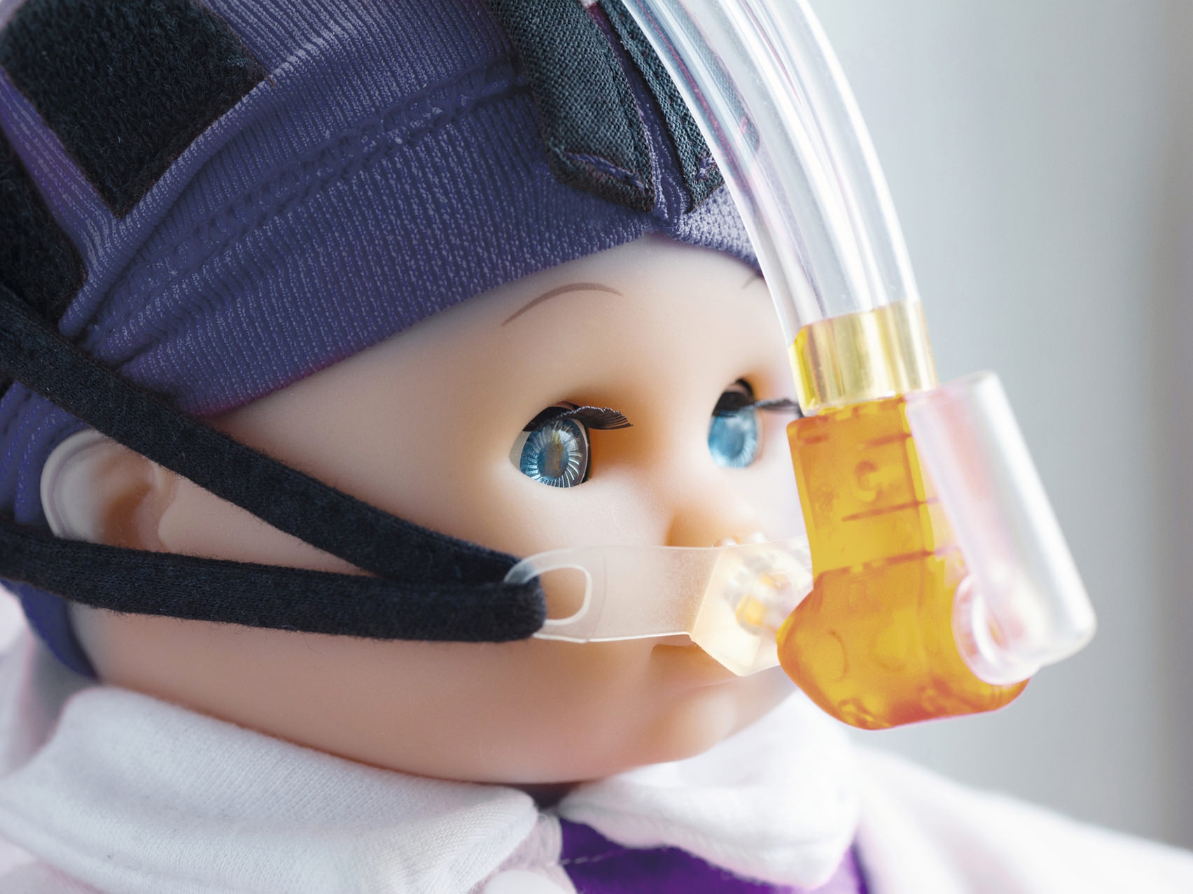 Detailný záber na tvár bábiky s dýchacou maskou.