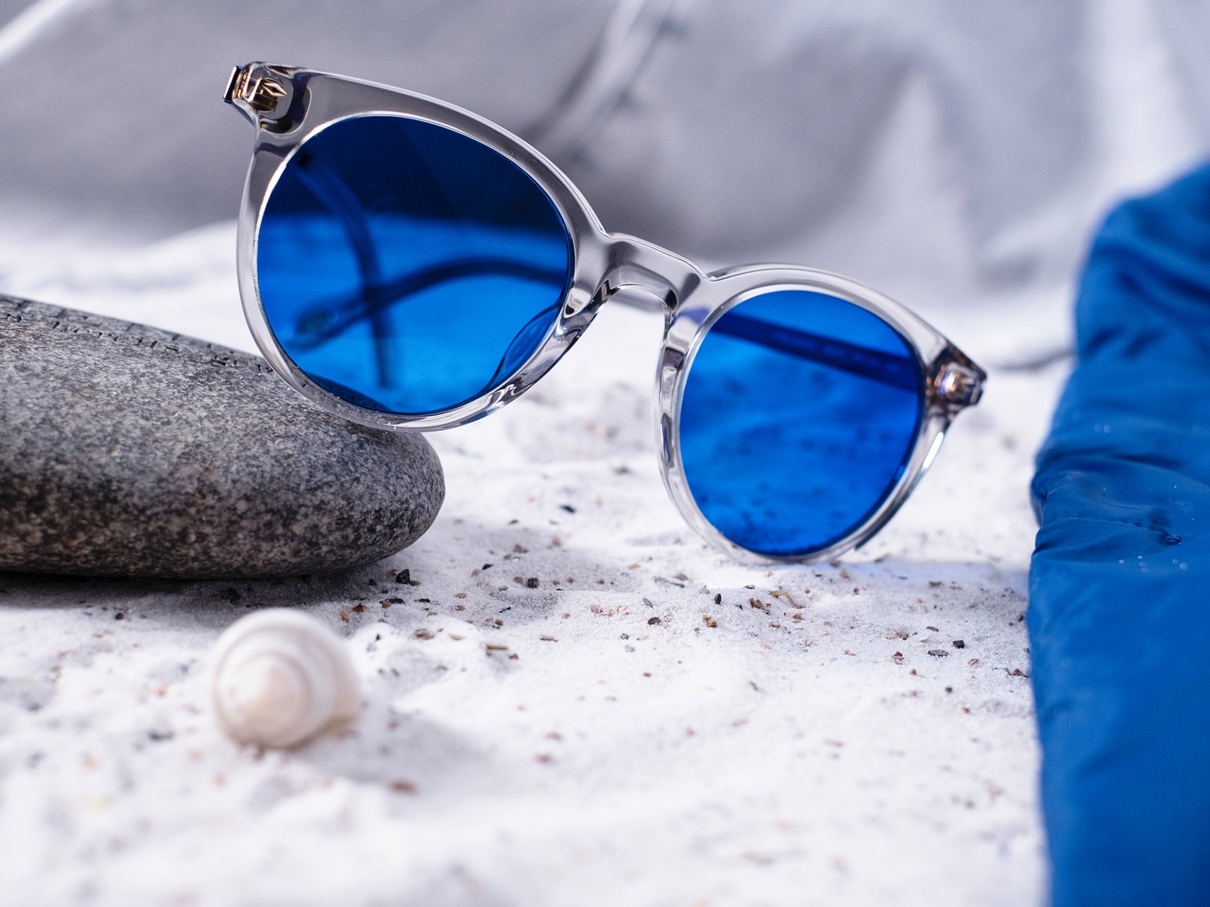Obrázok slnečných okuliarov s modrým odtieňom napoly položených na kameni