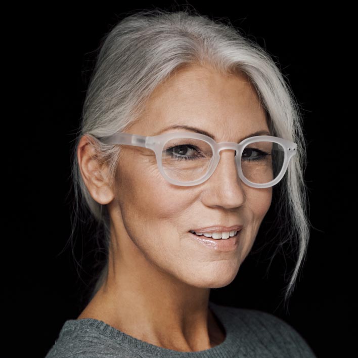 Žena so sivými vlasmi majúca biely rám so šošovkami ZEISS SmartLife Progressive. Geometrický sken tváre ukazujúci anatómiu tváre a merania rámu.